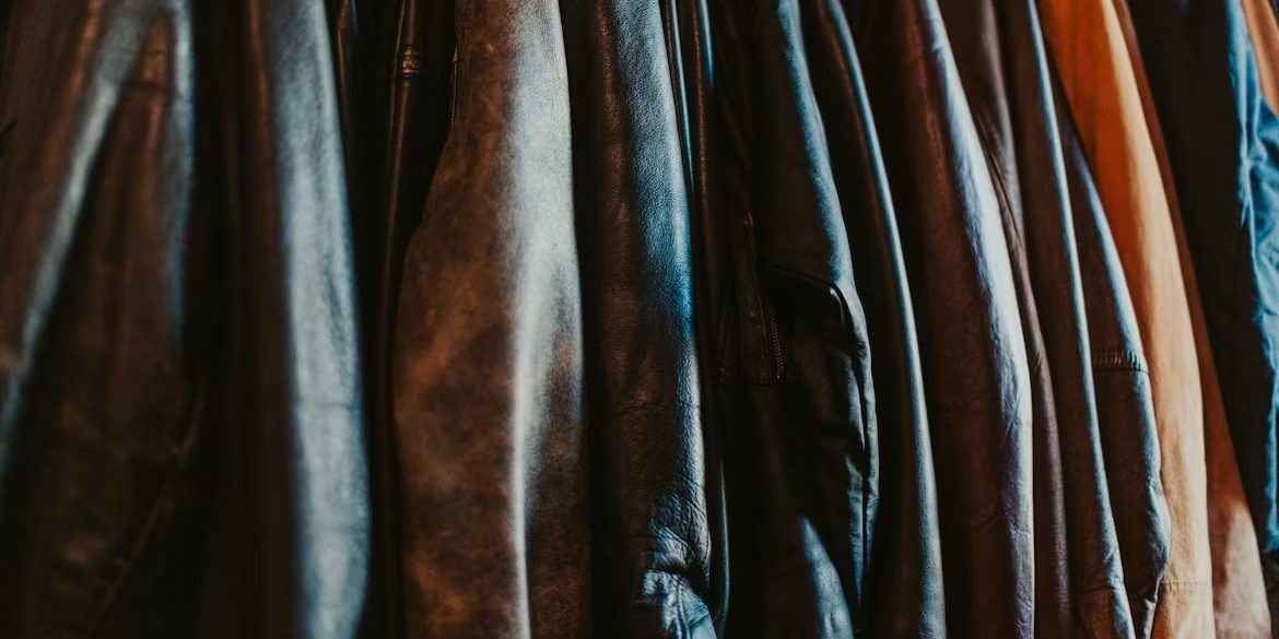 A close packed rail of worn leather motorcycle jackets in browns and blacks