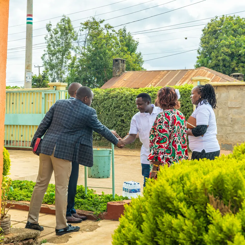 Two men shaking hands at a gateway while two women stand alongside them