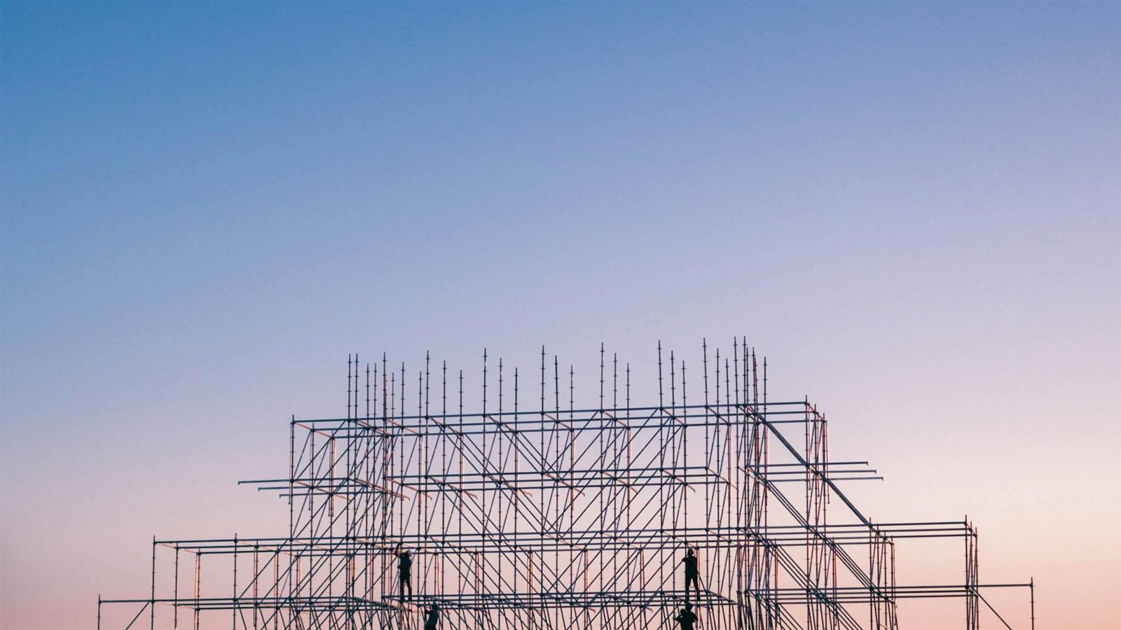 Scaffolding rising against a dusk sky, a structure halfway between plan and building.